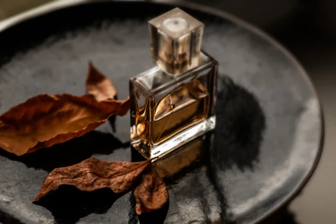 Un elegante frasco de perfume con hojas secas sobre una bandeja