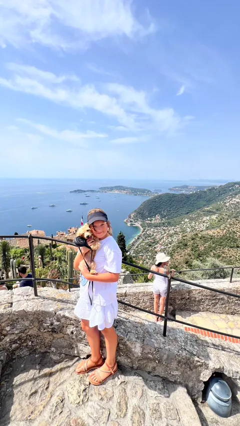Una niña con un perro pequeño en un mirador sobre la Costa Azul