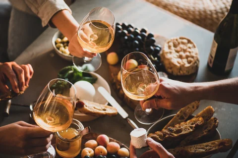 Comensales compartiendo vino, quesos y aperitivos franceses