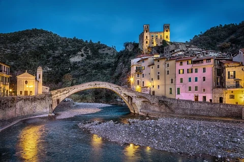 Casas, puente y castillo Doria iluminados al atardecer en Dolceacqua