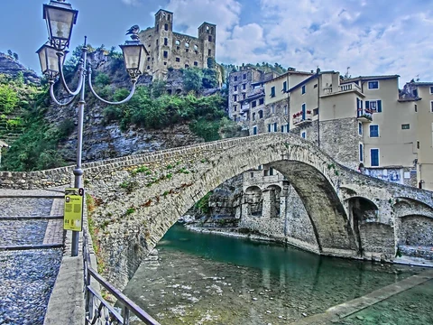 Antiguo puente de piedra sobre el río Nervia y castillo Doria en Dolceacqua