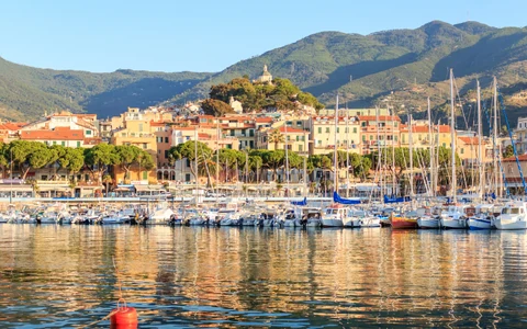 Yates en el puerto de Sanremo y el santuario de Madonna della Costa sobre la ciudad